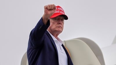 US President Donald Trump gestures as he boards Air Force One at Morristown Airport in Morristown, N.J. (AP Photo)