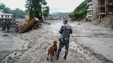 A policeman with a sniffer dog looks at the damage in the aftermath of flash floods in Devighat in the Nuwakot district in Nepal, Thursday, Aug 27, 2026. AP/PTI(AP08_27_2026_000110B)