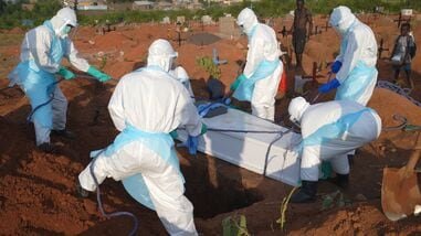 People in protective gear lower into a grave the coffin containing the remains of Jacques Lobo Dhena, who died of Ebola, during a burial service in Bunia, Ituri province, eastern Congo, Wednesday, Aug. 12, 2026. (AP Photo/Dieudonne Dirole)