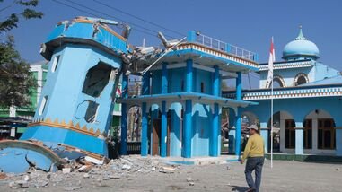 A man walks near an earthquake-damaged mosque in Reo, East Nusa Tenggara province, Indonesia, Monday, Aug. 17, 2026.