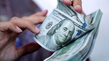 A worker counts US dollar banknotes at a currency exchange office.