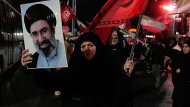 A woman holds up a poster of Iranian Supreme Leader Ayatollah Mojtaba Khamenei and waves a flag during a pro-government gathering at a square in Tehran, Iran, Tuesday, Aug. 11, 2026. (AP Photo/Vahid Salemi)