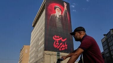 US-Iran war news LIVE: A man rides on his motorbike past a billboard with a message that reads in Farsi.