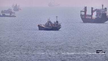 A small boat sails past cargo ships and other commercial vessels anchored in the Strait of Hormuz off Bandar Abbas, Iran, Wednesday, Aug. 5, 2026. (Amirhosein Khorgooi/ISNA via AP)