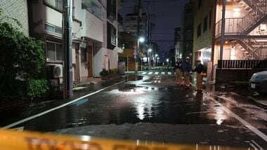 First responders from the Tokyo Fire Department stand on a street partially flooded in the early hours of Sunday, Aug. 23, following the rupture of a water pipe after an earthquake that struck the area and neighboring prefectures.