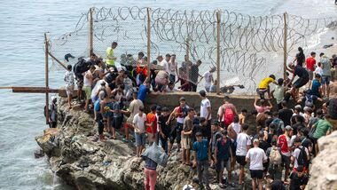People breach barbed wires as they attempt to cross from the Moroccan northern town of Fnideq to the Spanish enclave of Ceuta, Friday, July 31, 2026.