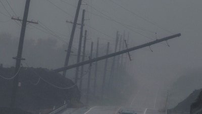 A vehicle drives near a downed utility pole dangling above Mamalahoa Highway during Hurricane Lala near Ocean View, Hawaii. (Stephen Lam/San Francisco Chroni)