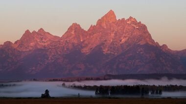 FILE PHOTO: Fog lays in the valley as the sun rises on the Tetons in Grand Teton National Park near the site of the Federal Reserve Bank of Kansas City's 2026 Jackson Hole economic symposium, in Jackson Hole, Wyoming