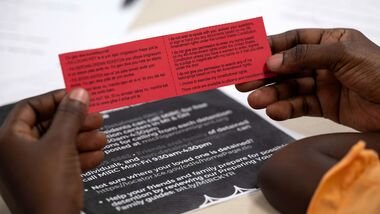 A Haitian woman holds a card with information in Creole and English to present to agents in case of an interaction with ICE, during an information session for people with Temporary Protected Status (TPS), hosted by the Haitian Network Group Detroit (HNGD), at St. David Episcopal Church in Southfield, Michigan, U.S., August 9, 2026.  REUTERS/Dieu-Nalio Chery