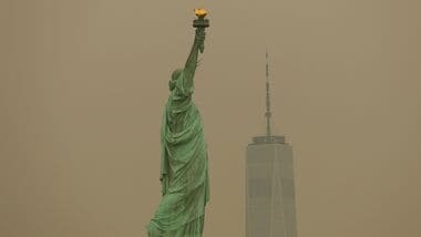 The Statue of Liberty in New York Harbor is seen through a cover of wildfire smoke in Jersey City, New Jersey, U.S., July 16, 2026. REUTERS/Mike Segar