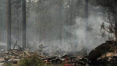A burned structure smolders due to a wildfire on Sunday, Aug. 2, 2026, in Spokane, Wash.
